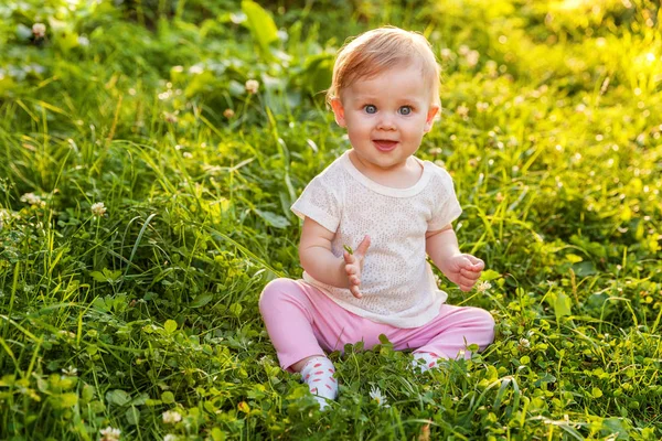 Zoete happy babymeisje zittend op het gras in park, Tuin, weide — Stockfoto