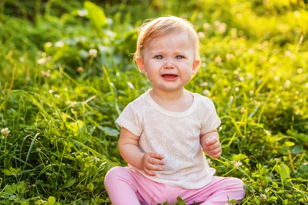 Édes sírás sikoltozó baba kislány ül a fűben park, kert, rét — Stock Fotó