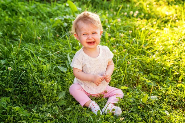 Édes sírás sikoltozó baba kislány ül a fűben park, kert, rét — Stock Fotó