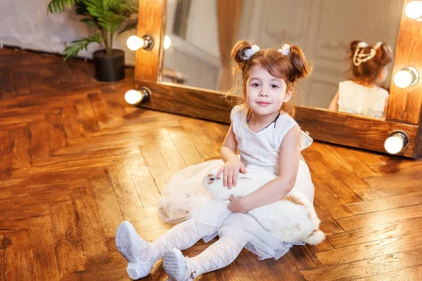 Menina sentada no chão e brincando com coelho branco no quarto moderno sobre espelho — Fotografia de Stock