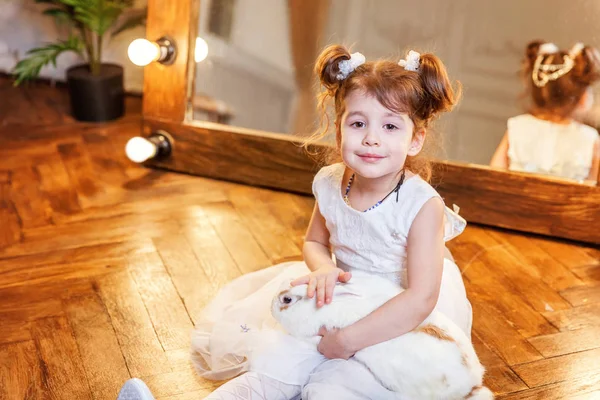 Katta oturan ve modern oda beyaz tavşan tavşan ile ayna üzerinde oynarken küçük kız — Stok fotoğraf