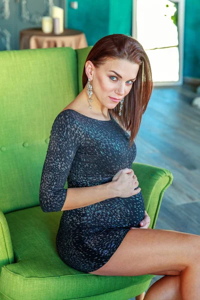 Mulher grávida sentada na cadeira em casa — Fotografia de Stock