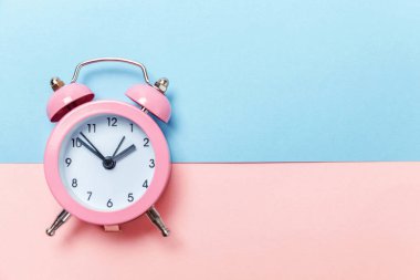 Vintage çalar saat göl kenarında mavi ve pembe pastel arka plan üzerinde