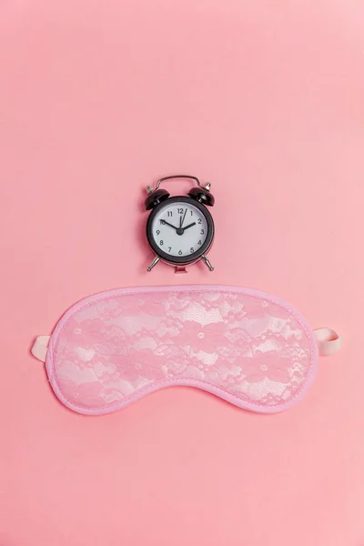 Máscara de dormir e despertador no fundo rosa — Fotografia de Stock