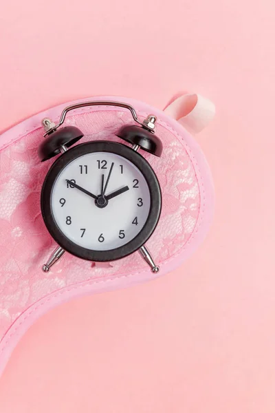 Máscara para dormir y despertador sobre fondo rosa —  Fotos de Stock