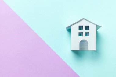 Minyatür beyaz oyuncak ev mavi ve mor pastel arka plan üzerinde