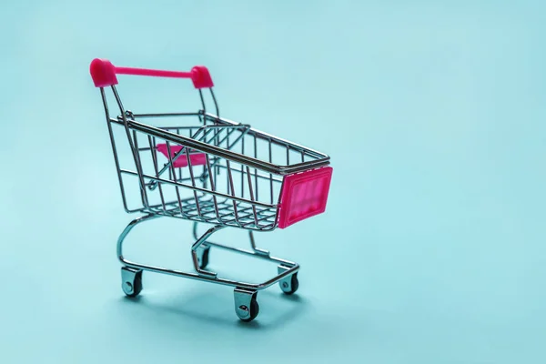 Kleine supermarkt kruidenier speelgoed push kar op blauwe achtergrond — Stockfoto