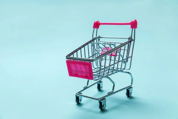 Small supermarket grocery toy push cart on blue background