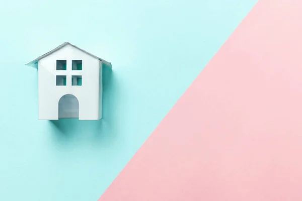 Miniaturowe zabawki biały dom na tle pastel niebieski i różowy — Zdjęcie stockowe