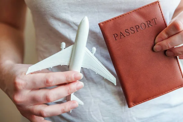 旅游必需品。女妇女手拿着小玩具模型飞机和护照 — 图库照片