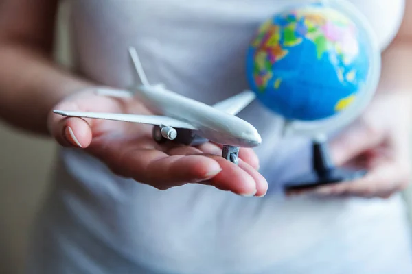 Eller kadın kadın küçük oyuncak model uçak ve küre harita tutarak — Stok fotoğraf