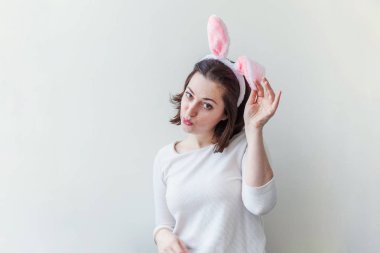 Mutlu Paskalya tatil kutlama bahar kavramı. Beyaz arka plan üzerinde izole Paskalya gününde tavşan kulakları giyen genç kadın