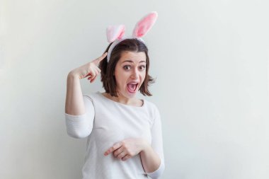 Mutlu Paskalya tatil kutlama bahar kavramı. Beyaz arka plan üzerinde izole Paskalya gününde tavşan kulakları giyen genç kadın