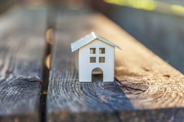 Miniatur-weißes Spielzeugmodellhaus im Holzhintergrund. Ökodorf, abstrakter ökologischer Hintergrund — Stockfoto