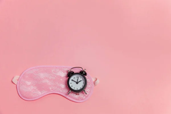 Máscara de dormir e despertador no fundo rosa — Fotografia de Stock