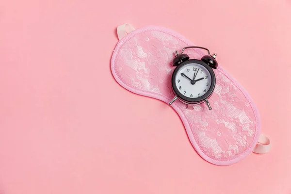 Máscara de dormir e despertador no fundo rosa — Fotografia de Stock