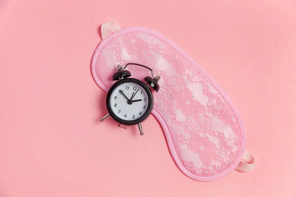 在粉红色背景的睡眠面罩和闹钟 — 图库照片