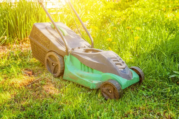 Lawn mower cutting green grass in backyard