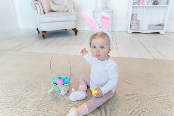 Niña pequeña con orejas de conejo el día de Pascua y jugando con huevos pintados — Foto de Stock