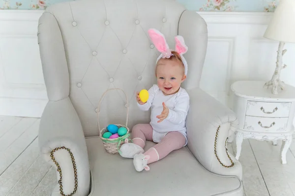 Lilla barnflickan bär bunny öron på påskdagen och leker med målade ägg — Stockfoto