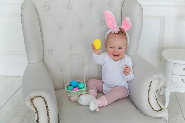 Lilla barnflickan bär bunny öron på påskdagen och leker med målade ägg — Stockfoto