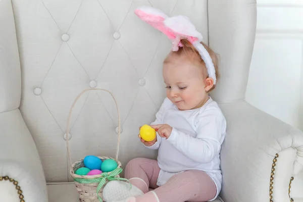Bambina bambina che indossa orecchie di coniglio il giorno di Pasqua e giocare con uova dipinte — Foto Stock