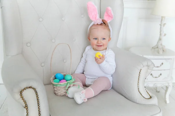 Niña pequeña con orejas de conejo el día de Pascua y jugando con huevos pintados —  Fotos de Stock