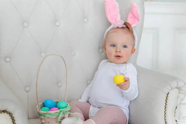 Lilla barnflickan bär bunny öron på påskdagen och leker med målade ägg — Stockfoto