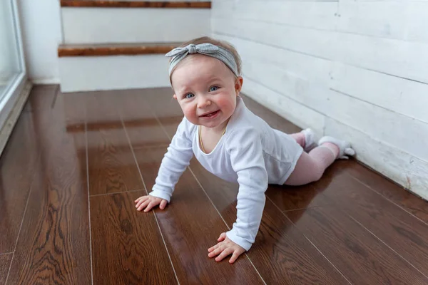 Petite petite fille rampante d'un an assise sur le sol dans un salon lumineux près de la fenêtre souriante et riante — Photo