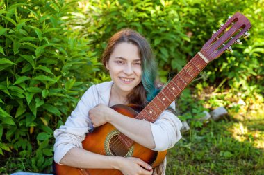 Otların arasında oturan ve gitar çalmak genç kadın