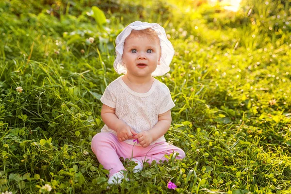 Dulce niña feliz sentado en la hierba en el parque, jardín, prado —  Fotos de Stock