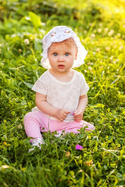 Dulce niña feliz sentado en la hierba en el parque, jardín, prado —  Fotos de Stock