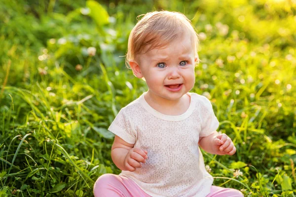 Dulce niña feliz sentado en la hierba en el parque, jardín, prado —  Fotos de Stock