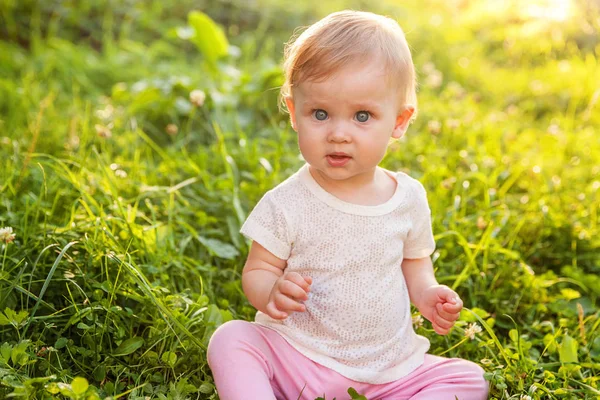 Dulce niña feliz sentado en la hierba en el parque, jardín, prado —  Fotos de Stock