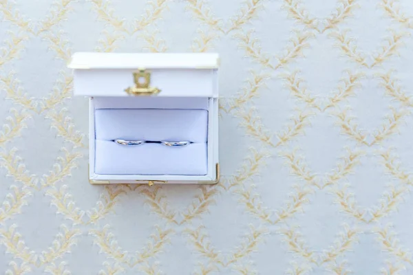 Two beautiful wedding rings on white jewelry box on light background — Stock Photo, Image