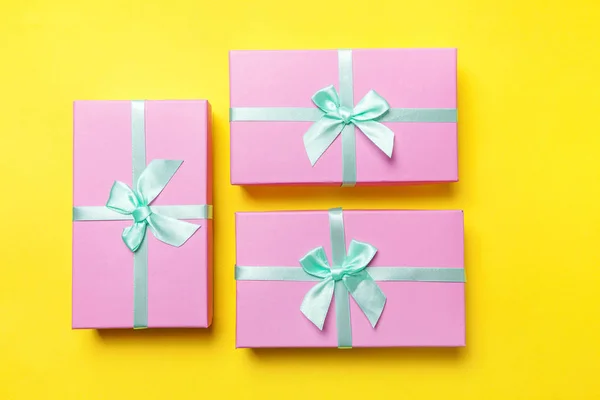 Christmas New Year birthday valentine celebration present romantic concept. Three pink gift boxes isolated on yellow background