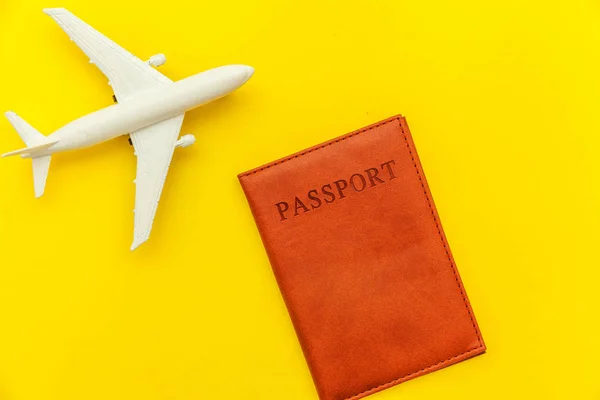 Minimal simple flat lay travel adventure trip concept with plane and passport on yellow trendy modern background