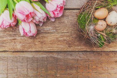 Paskalya yumurta yuva rustik ahşap zemin üzerine yosun ve pembe taze Lale buketi ile
