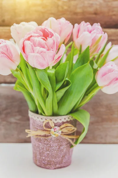 Bouquet of fresh pink tulips flowers on rustic white wooden background