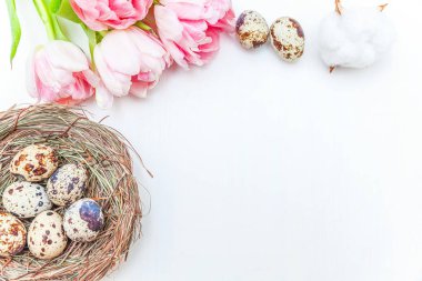 Paskalya yumurtaları yuvadan pamuk ve pembe taze tulip buket rustik Beyaz ahşap zemin üzerinde