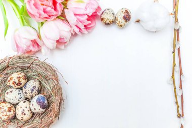 Paskalya yumurtaları yuvadan pamuk ve pembe taze tulip buket rustik Beyaz ahşap zemin üzerinde