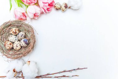 Paskalya yumurtaları yuvadan pamuk ve pembe taze tulip buket rustik Beyaz ahşap zemin üzerinde