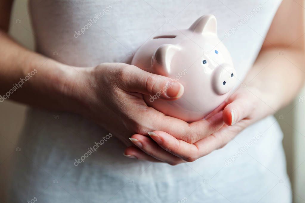 Woman hands holding pink piggy bank