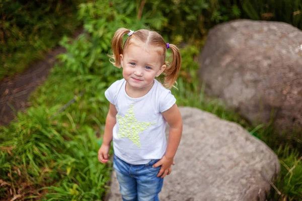 Ritratto di felice carina bambina all'aperto. Ragazzo palying nel parco, giardino, foresta fatata contro grandi rocce — Foto Stock