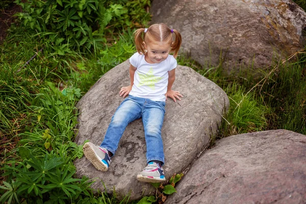 Ritratto di felice carina bambina all'aperto. Ragazzo palying nel parco, giardino, foresta fatata contro grandi rocce — Foto Stock
