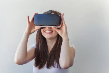 Beyaz arka plan üzerinde sanal gerçeklik Vr gözlük kask kulaklık kullanarak giyen gülümseme genç kadın