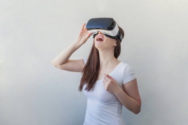 Beyaz arka plan üzerinde sanal gerçeklik Vr gözlük kask kulaklık kullanarak giyen gülümseme genç kadın