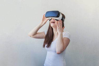 Beyaz arka plan üzerinde sanal gerçeklik Vr gözlük kask kulaklık kullanarak giyen gülümseme genç kadın
