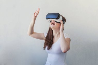 Beyaz arka plan üzerinde sanal gerçeklik Vr gözlük kask kulaklık kullanarak giyen gülümseme genç kadın