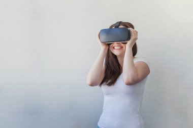 Beyaz arka plan üzerinde sanal gerçeklik Vr gözlük kask kulaklık kullanarak giyen gülümseme genç kadın